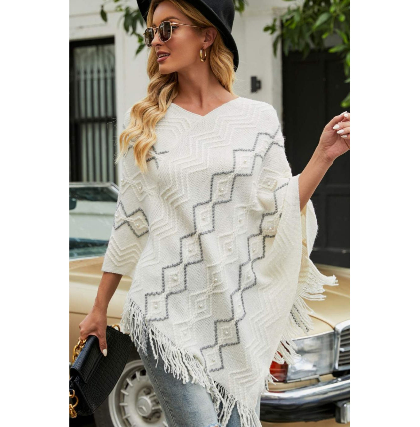 Model wearing white poncho with faux pearl and fringe trim