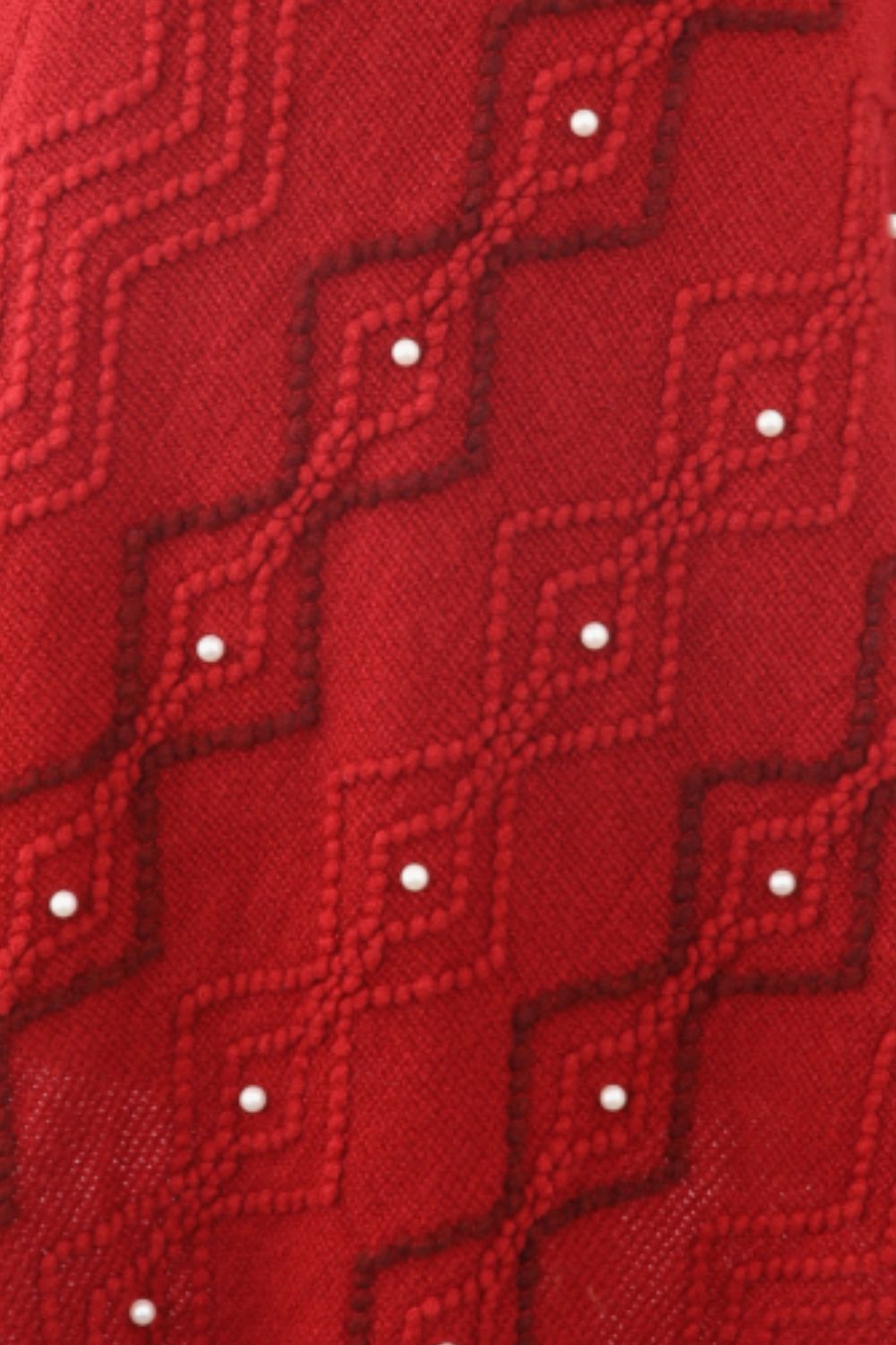 Close up of Red poncho with faux pearl and fringe trim