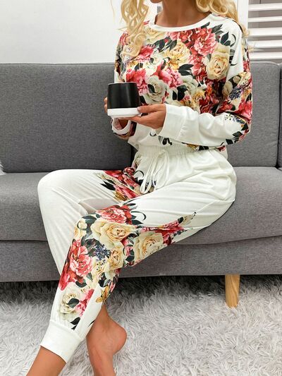 Model sitting on couch holding cup of coffee wearing white pajama set with flower print