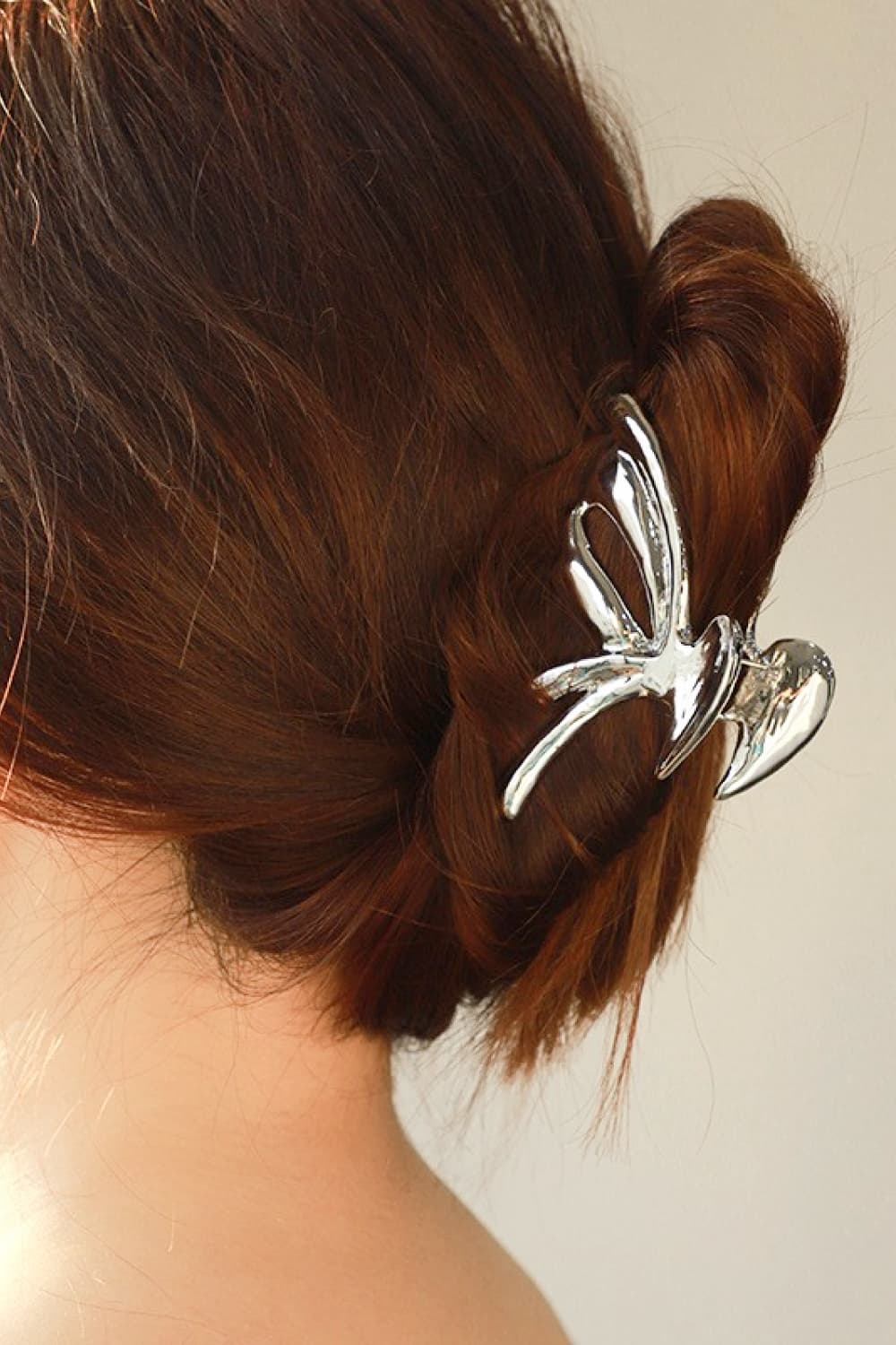 Photo of woman wearing polished silver color butterfly claw clip in hair
