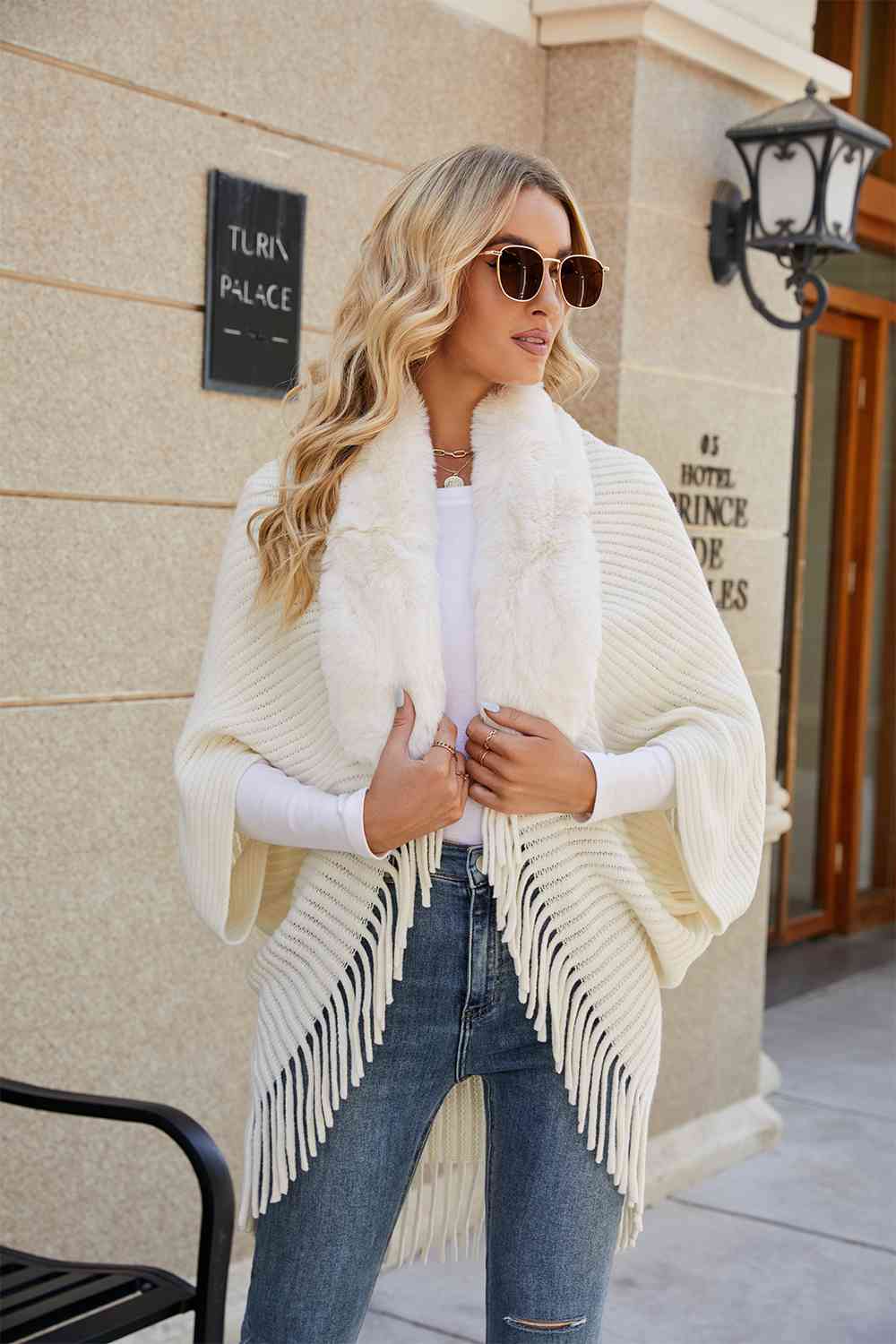 Model wearing Ivory open front poncho with fringe and faux fur trim