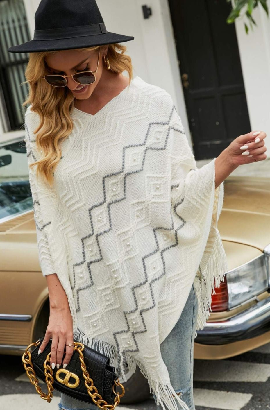 Model wearing white poncho with faux pearl and fringe trim