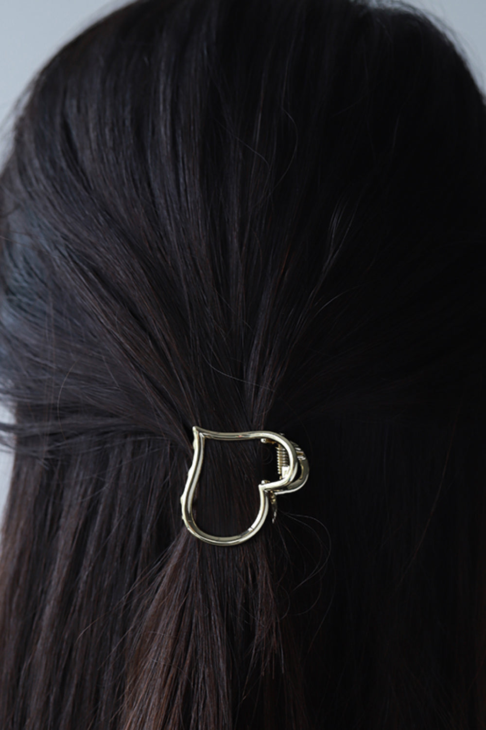Woman wearing gold plated heart-shaped claw clip
