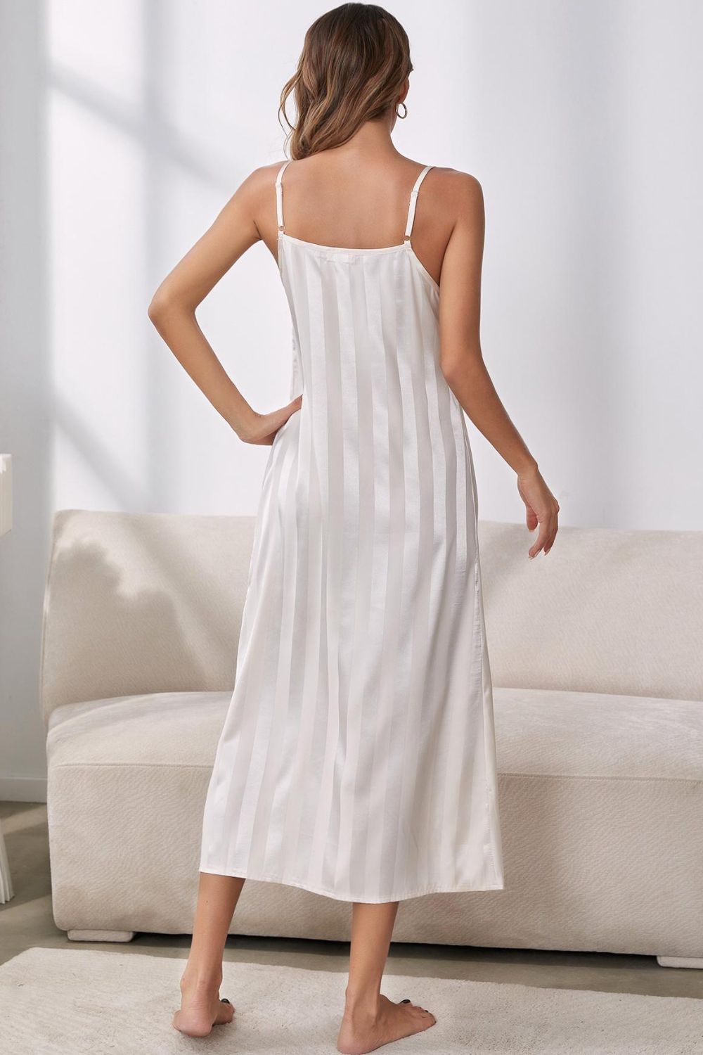 Back view of woman standing in front of sofa wearing beige striped nightgown