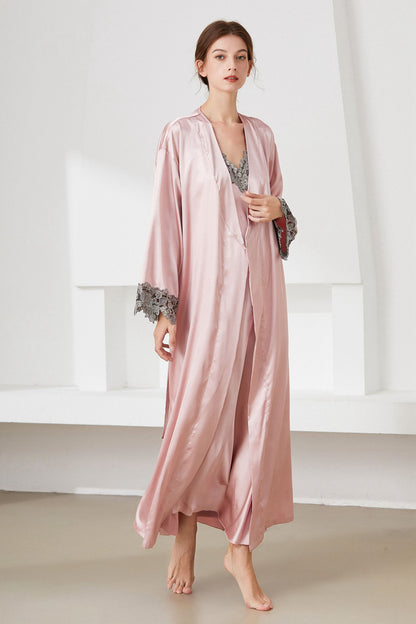 Angle view of woman standing wearing pink satin  nightdress and matching robe, with lace trim