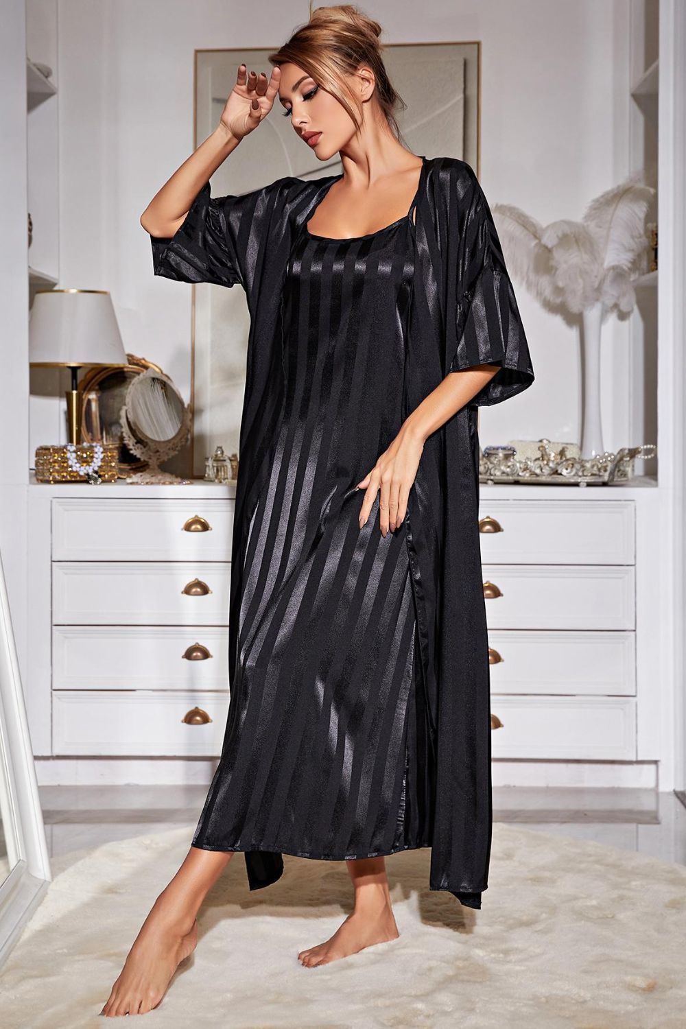 Angle view of woman standing in front of dresser wearing black striped nightgown and matching black striped robe