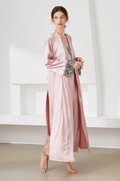 Side view of woman standing wearing pink satin  nightdress and matching robe, with lace trim