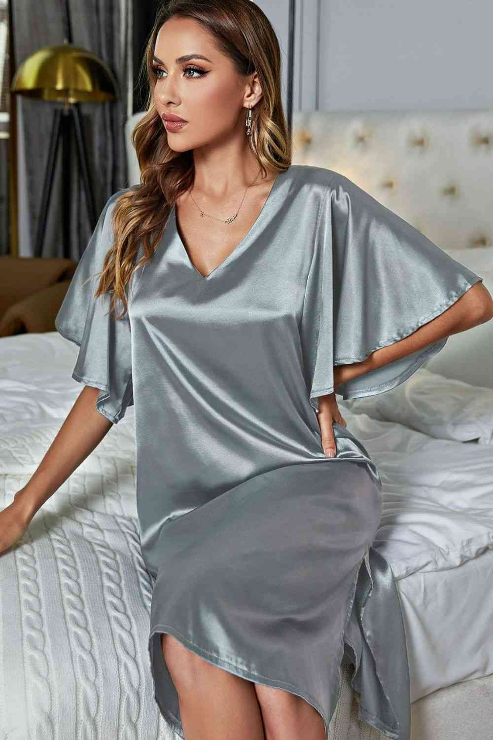 Model sitting on bed wearing silver knee length nightgown