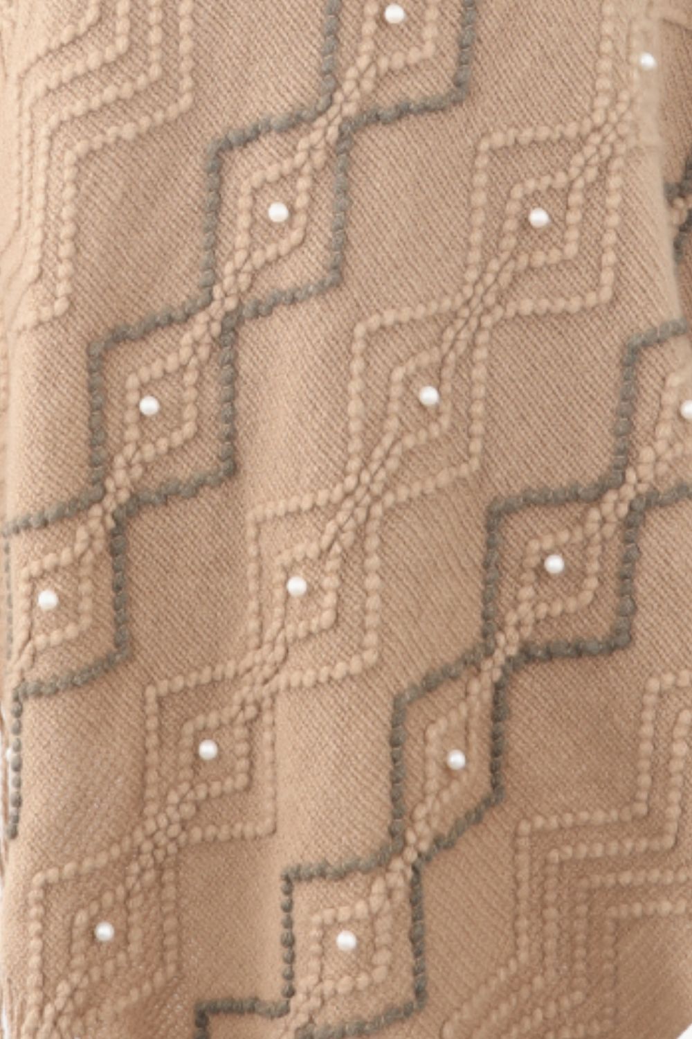 close up of Beige poncho with faux pearl and fringe trim