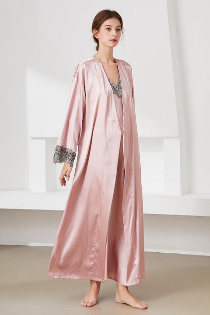 Angle view of woman standing wearing pink satin  nightdress and matching robe, with lace trim