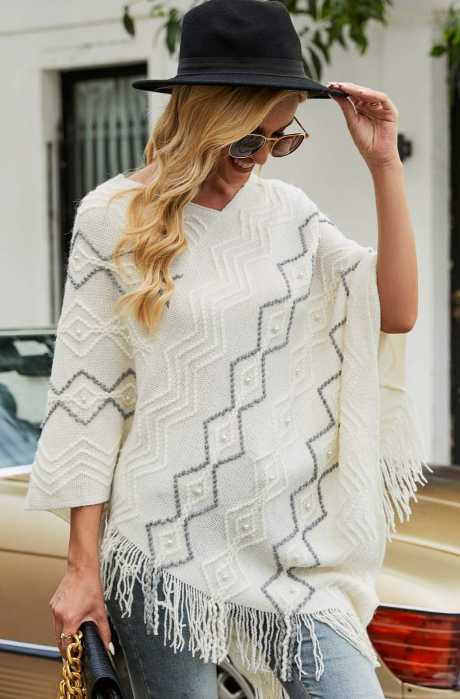 Model wearing white poncho with faux pearl and fringe trim