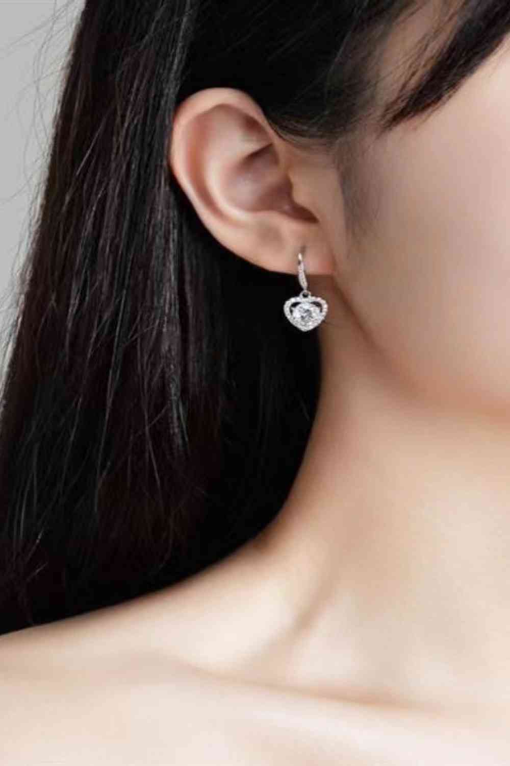 Model wearing Clear Moissanite heart earrings with zircon accent stones set in platinum plated sterling silver